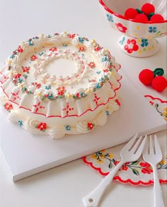 a cake sitting on top of a white cutting board next to a bowl and fork