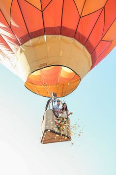 two people in a hot air balloon flying through the sky