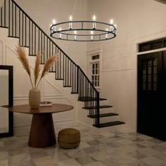 a foyer with a chandelier, table and vase on the floor next to it