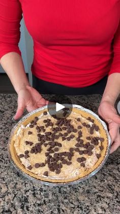 a woman holding a pie with chocolate chips on it