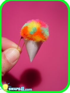 a hand holding a tiny colorful object in it's tip and the tip is white