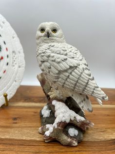 an owl figurine sitting on top of a piece of wood