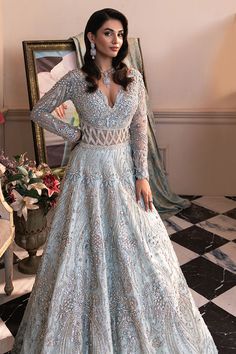 a woman in a blue gown standing next to a mirror and looking at the camera