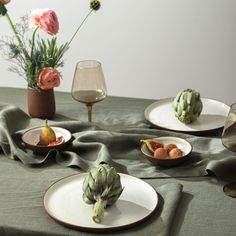 a table topped with plates and bowls filled with food next to flowers in vases