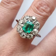 An incredible vintage cluster ring featuring an octagonal cut emerald, surrounded by eight old-cut diamonds, weighing an estimated total of 2.00 carats, claw set and mounted in 18ct white gold. A fantastic dress, statement or engagement ring from the 1940s to 1950s. Circa 1940-1950. Stamped and tested as 18ct gold. The estimated diamond colour is K-L. The estimated diamond clarity is Si1. The estimated total diamond weight is 2.00ct. The emerald measures approximately 7.65mm x 6.2mm x 4.00mm. Th Cluster Engagement Ring Emerald, Classic Green Cluster Diamond Ring, Classic Cluster Emerald Ring, Emerald Cluster Ring In White Gold, Classic Cluster Emerald Diamond Ring, Classic Emerald Ring With Prong Setting In Cluster Shape, Classic Cluster Emerald Ring With Prong Setting, Classic Green Cluster Emerald Ring, Vintage Emerald Ring With Halo Diamond Setting