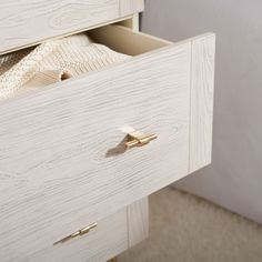 an open drawer in a white dresser with gold handles and knobs on the drawers