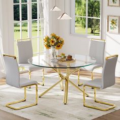 a glass dining table with white chairs and flowers on the table in front of windows