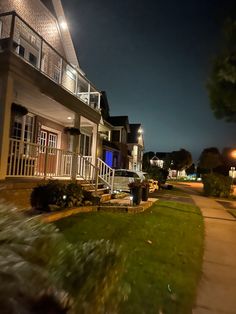 a street at night with cars parked on the side and houses in the back ground