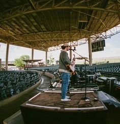 a man standing on top of a stage with a guitar in front of an audience