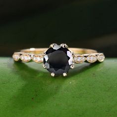 a black and white diamond ring sitting on top of a green surface