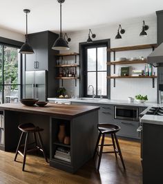 a kitchen with black cabinets and wooden floors