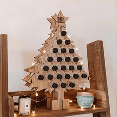 a wooden christmas tree on a shelf with lights