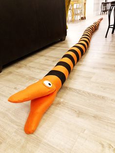 an orange carrot laying on the floor in front of a black couch with eyes painted on it