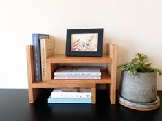 a small wooden shelf with books and a potted plant on the table next to it