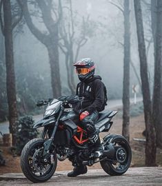 a man riding on the back of a motorcycle down a road in front of trees