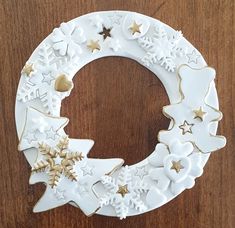 a white and gold decorated christmas wreath on a wooden surface with stars, snowflakes and crescent