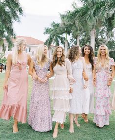 a group of women standing next to each other on top of a lush green field