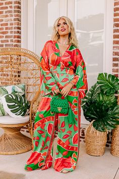 - This stunning jumpsuit is a ticket to sunshine vibes! Featuring a bold vibrant print and a chic satin finish, this trendy wide leg jumpsuit promises to steal the spotlight and keep you feeling fabulous. - Unlined material with a pink, orange, and green hued abstract botanical print with a satin finish - A v-cut neckline and a v-cut back with a tie detail - Long. loose sleeves - A waistline with an elastic back and an attached tie closure belt - A relaxed silhouette that ends in wide hemlines Chic Orange Jumpsuits And Rompers For Vacation, Chic Orange Jumpsuit And Romper For Vacation, Summer Party Jumpsuits Maxi Length, Trendy Wide-leg Jumpsuits And Rompers For Vacation, Trendy Wide Leg Jumpsuits And Rompers For Vacation, Trendy Wide-leg Jumpsuits For Vacation, Trendy Orange Jumpsuits And Rompers For Beach, Multicolor Wide-leg Jumpsuits For Beach, Multicolor Wide-leg Jumpsuits For The Beach