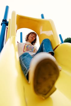 a woman sitting on top of a yellow slide