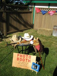 an old fashioned photo booth with hats and other items on the grass in front of a fence