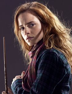 a woman with long red hair holding a harry potters wand in her right hand