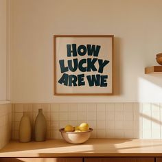 a bowl of lemons sitting on top of a counter next to a framed poster