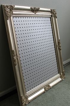 a silver framed mirror sitting on top of a carpeted floor next to a wall