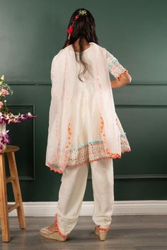 Off white three fourth sleeves kurta with mirror work embroidery on border and pom pom detailing. Paired with pom pom detailing petal hem dhoti pant and dupatta.
Components: 3
Pattern: Embroidered
Type Of Work: Mirror Work, Pom Pom
Neckline: Round
Sleeve Type: Three Fourth
Fabric: Pure Chanderi Silk, Dola Silk, Organza; Lining: Mul Mul Cotton
Color: Off White
Other Details: 
Closure: 
Kurta: Back zip
Dhoti pant: Elasticated
Note: The hair accessory and potli bag shown in the image is not for sal Anarkali White Pant Set For Festive Occasions, Festive Straight Kurta Sharara With Tassels, Festive Sharara With Tassels And Straight Kurta, Traditional Festive Pant Set With Mirror Work, Spring Cotton Salwar Kameez With Mirror Work, Off White Gota Work Sets For Navratri, Diwali Sharara With Tassels And Straight Kurta, White Anarkali Pant Set, Spring Cotton Traditional Wear With Mirror Work