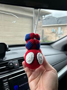 someone is holding up a red and white stuffed animal in their car's dashboard