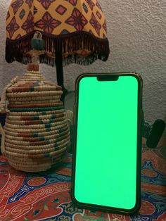 a cell phone sitting on top of a table next to a basket with a green screen