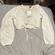 Brand New With Tags! Beautiful Blouse With Embroidery Detailing In The Front And Lovely Open Back That Ties At Waist. Has The Smallest Tear On Upper Back Right Shoulder. Fabric Is Very Delicate Casual Lace Blouse With Lace Work, Casual Floral Embroidered Lace Top, Summer Long Sleeve Embroidered Lace Top, Casual Long Sleeve Lace Blouse, Long Sleeve Embroidered Lace Top For Summer, White Chikankari Embroidery Peasant Top, White Lace Top With Broderie Anglaise, Casual Lace Tops With Floral Embroidery, Casual White Blouse With Lace Work