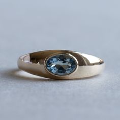 a gold ring with a blue stone in the center on a gray surface, close up