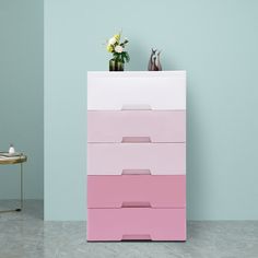 a pink and white chest of drawers in a blue room with flowers on the top