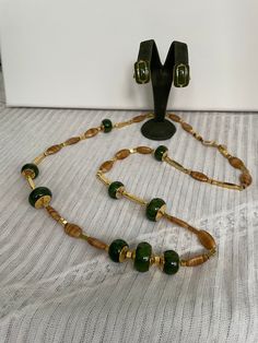 "Attention: *I can not ship to Australia at the moment due to shipping restrictions.* Also please note that shipments to the United States are taking longer than usual. This is a stunning vintage Lanvin green beaded necklace and green enameled clip on earrings set. The necklace is long with toggle closure and has flattened round green plastic beads with gold tops and bottoms, long and short gold cubed and rectangle spacer beads and brown swirled flat oval beads. It is signed \"Lanvin, Paris\". T Vintage Green Jewelry With Polished Beads, Handmade Retro Green Beaded Necklace, Vintage Green Round Beads Jewelry, Vintage Green Round Bead Jewelry, Vintage Green Round Beaded Jewelry, Retro Green Beaded Necklace For Gift, Retro Green Beaded Necklaces, Vintage Lanvin, Gold Tops