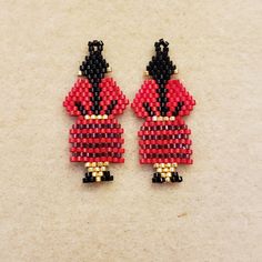 two red and black beaded ladybug earrings on top of a white surface