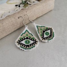 "Green beaded evil eye earrings.  ♥ SIZE  Earrings are approximately 4.5*3.5 cm (1.77\" * 1.4\") without hook_ ♥ 100% handmade ♥ Very light ♥ If you like this item in a different color - send me a message, please. Feel free to communicate with me Pattern - GaligaPatterns Listing : https://www.etsy.com/listing/1129373153/beaded-earrings-patterns-beading-pattern Advice on use and care * Never wear any jewelry while bathing or showering. Chlorine can cause damage. Please do not swim and did not take a shower in beaded jewelry * Try to avoid the drop, shock and compression of jewelry from beads Since this is handmade item, every new good may be vary slightly, but the overall look will match that shown on the photo. The color transfer depends on the settings of your monitor." Alien Seed Bead Earrings, Evil Eye Seed Bead Earrings, Beaded Evil Eye, Earrings Patterns, Protection Jewelry, Tear Drop Earrings, Evil Eye Earrings, Seeing Eye, Packing Jewelry