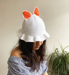 a woman wearing a white knitted hat with orange ears