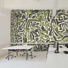 two desks in front of a wall with green and white designs on it,