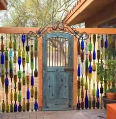 a wooden gate with glass bottles hanging from it's sides and a green door