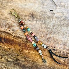 a long beaded keychain with various beads and charms hanging from it on a wooden surface