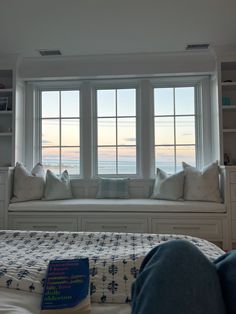 a bedroom with a large window seat next to the bed and bookshelves on the wall