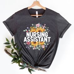 Nursing Assistant Shirt - Soft and comfortable shirt options are made from soft cotton (heather colors also contain polyester). Professionally printed with attention to detail we know our tees will become your favorite. - Soft t-shirts with quality shirt print - Fast customer service - We are here to help answer any questions! - Many different color and size options SIZING INFO Our unisex tees have a regular t-shirt fit. Width and length measurements for all sizes can be seen in the size chart i Heather Grey Graphic Tee With Text Print, Heather Grey Graphic Tee With Letter Print, Heather Grey Cotton T-shirt With Letter Print, Assistant Nurse, Nursing Assistant, Nurse Appreciation, Nurse Gifts, Unisex Shirt, Shirt Print