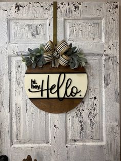 a door hanger with the word hello written in black on it and a bow