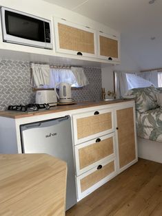 a kitchen area with a microwave, sink and stove top oven next to a bed