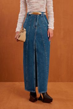 A high rise denim maxi skirt with a paneled design and center front slit. — High waisted — Angular panel design — Center front slit — Front pockets Maxi Denim Skirt, Evening Flats, Sandal Platform, Drape Sleeves, Denim Maxi, Denim Maxi Skirt, Kick Flares, Cult Gaia, Design Center