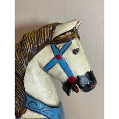 a white horse statue with blue harness on it's head and neck, standing against a wall