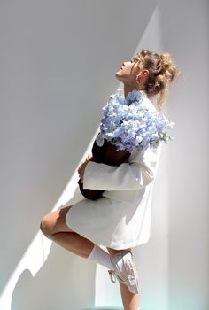 a woman in white dress holding blue flowers