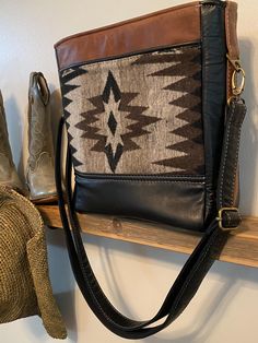 Handcrafted Southwest Cross-Body Tote Handbag.  Wool gray and brown tone design is surrounded by black and brown leather on both front and back.  Front of bag offers a zipper pocket.  Back of bag features a slip pocket with black leather pipping.   Interior is completely padded on all sides with waterproof canvas in striking gold with black leather pipping and includes a padded zipper pocket and two padded slip pockets, making this small bag a five pocket wonder.   With the addition of six metal Brown Leather Trim Shoulder Bag For On-the-go, Brown Rectangular Bag With Leather Trim, Travel Brown Saddle Bag With Leather Backing, Black Leather Lined Crossbody Bag, Black Leather Lining Crossbody Bag, Black Leather Crossbody Satchel, Black Leather Crossbody Saddle Bag, Black Saddle Crossbody Bag With Leather Handles, Black Saddle Bag With Leather Handles For Everyday