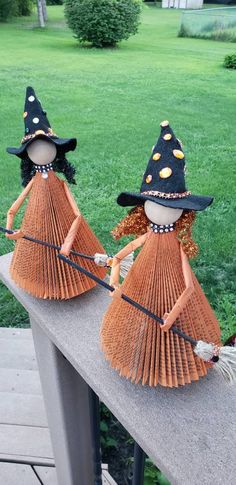 two scarecrows made out of paper are sitting on a rail in front of some grass