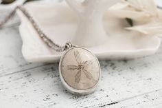 "I love these charming tiny treasures of the sea! Are you an ocean lover? Display your love of the sea with this little treasure!  This fossilized sand dollar / sea biscuit necklace is framed in a hand made sterling silver bezel and hangs from a sterling chain. Pendant size will vary but measure approximately 1\". ✽ Sterling Silver Setting ✽ Sterling Chain 16\"- 18\"  ✽ Real Sand Dollar ✽ Beautifully packaged ready for gift giving This necklace is made to order. The fossil may be slightly differ Beach Pendant Jewelry With Engraving, Beach Engraved Pendant Jewelry, Engraved Pendant Necklace For Beach, Ocean-inspired Jewelry With Lobster Clasp And Round Pendant, Ocean-inspired Round Jewelry With Starfish Charm, Handmade Ocean-inspired Round Pendant Jewelry, Sterling Silver Ocean-inspired Necklaces, Ocean-inspired Sterling Silver Necklaces, Handmade Ocean-inspired Jewelry Gift